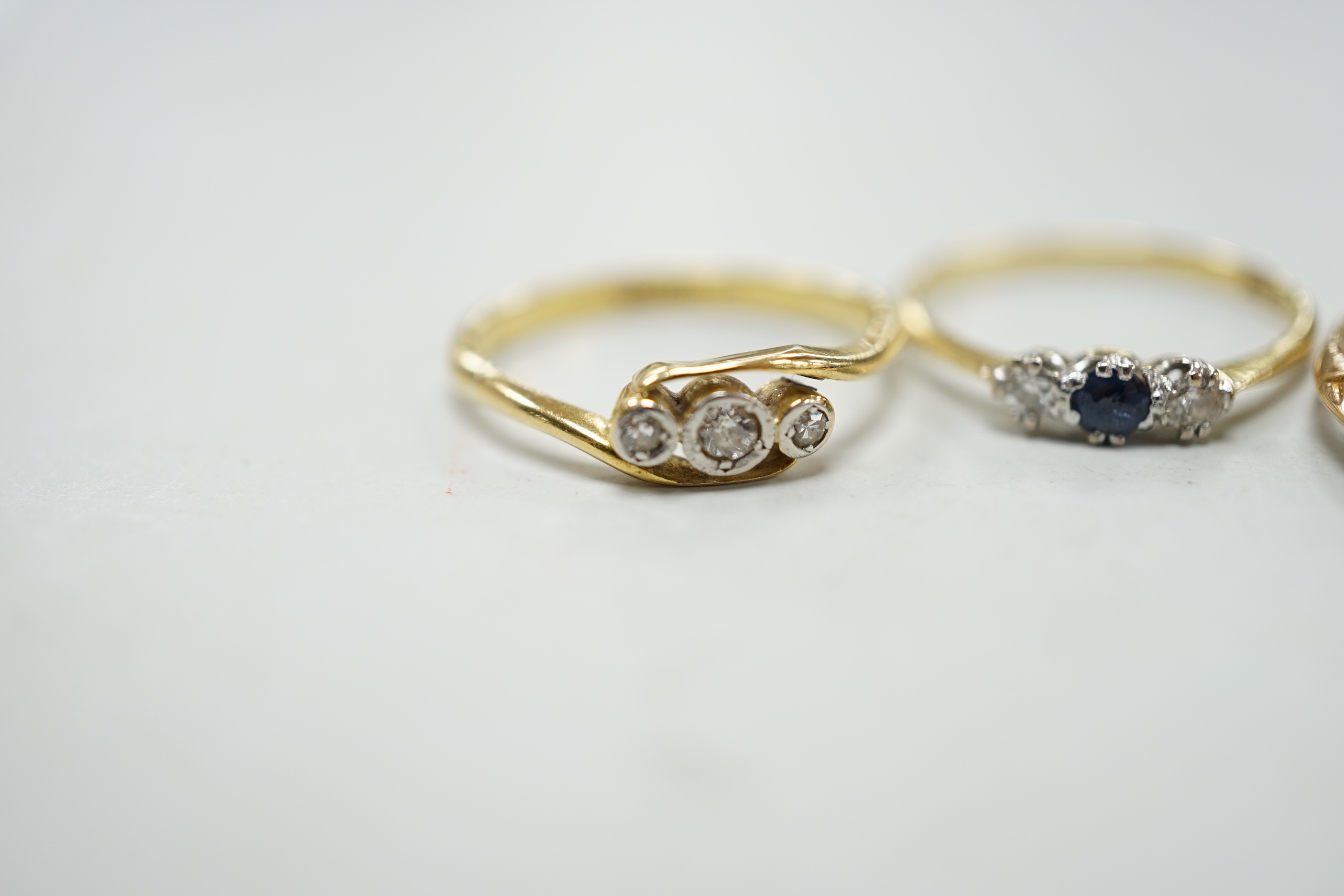 Two 18ct rings including illusion set three stone diamond and sapphire and diamond three stone and a yellow metal and graduated five stone diamond set half hoop ring, gross weight 5.8 grams.